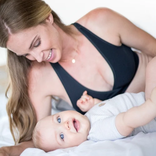 Mom in a black nursing bra smiling down at her baby