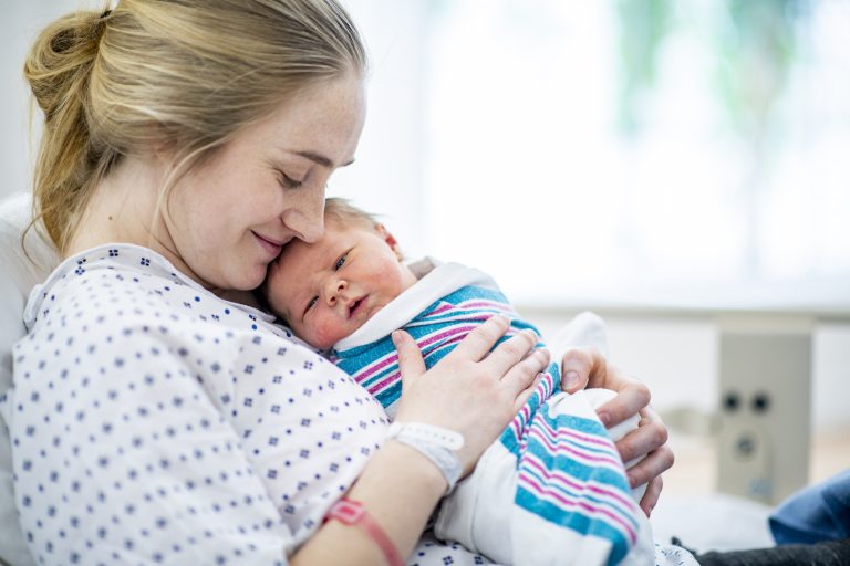 New mom holds her baby in hospital bed