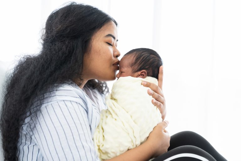 A new mom kisses her newborn baby