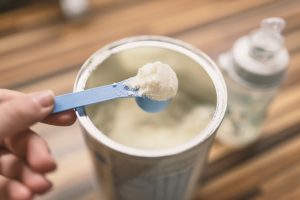 Powdered baby formula being scooped out of the container