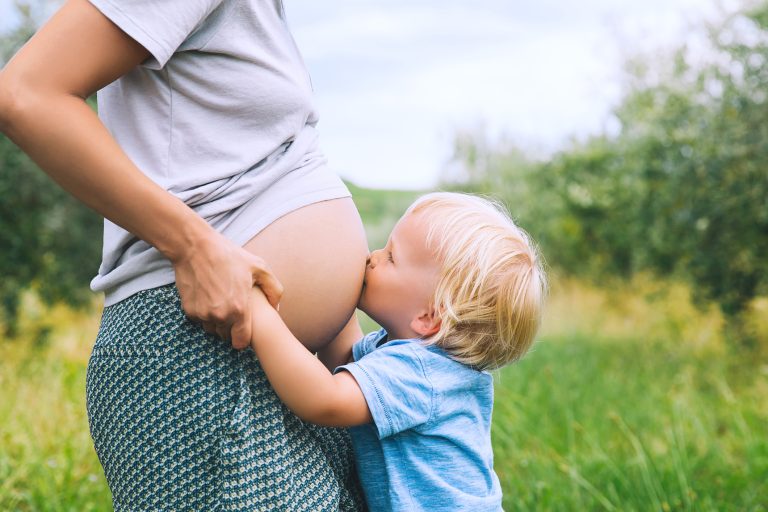 A little boy kisses his mom's pregnant belly