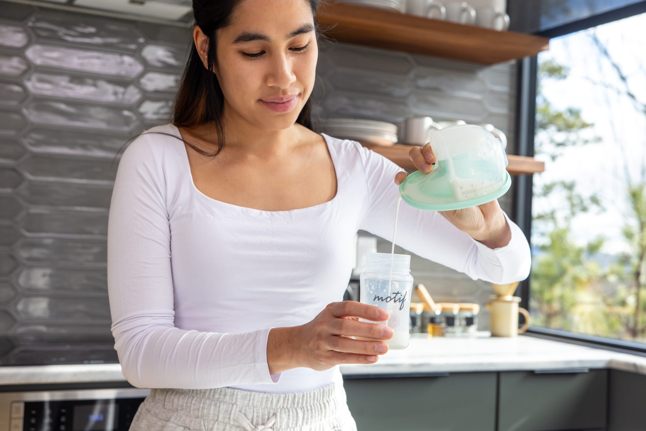 Mom pouring milk from a Motif Aura Glow Image showing a mom in her kitchen pouring milk from a Motif Aura Glow into a bottle