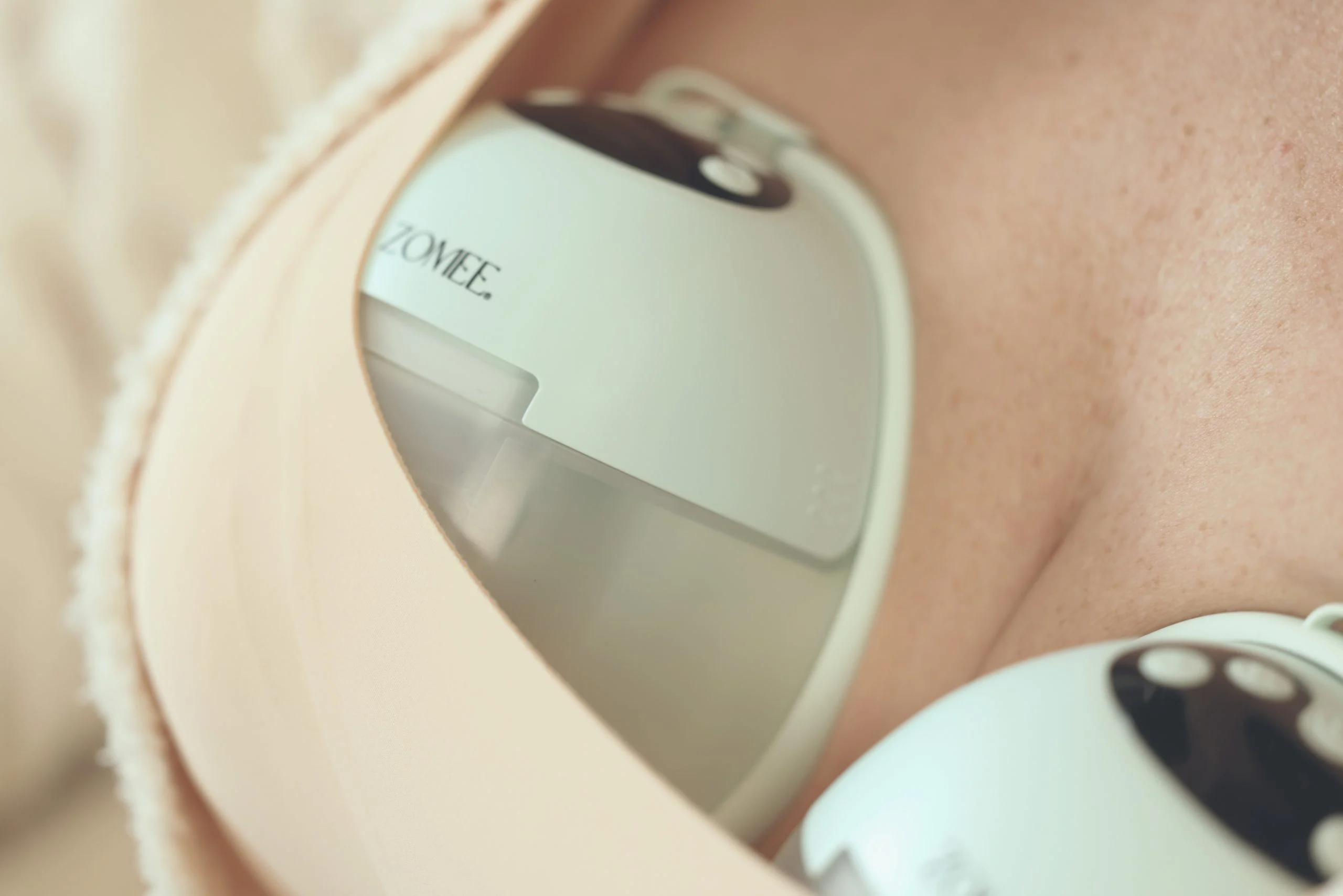 Close-up of the Zomee Mother’s Nature W1 warming wearable breast pump worn discreetly inside a nursing bra